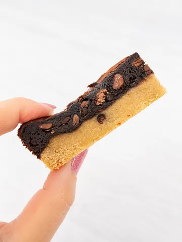 A hand holding a piece of chocolate cake.