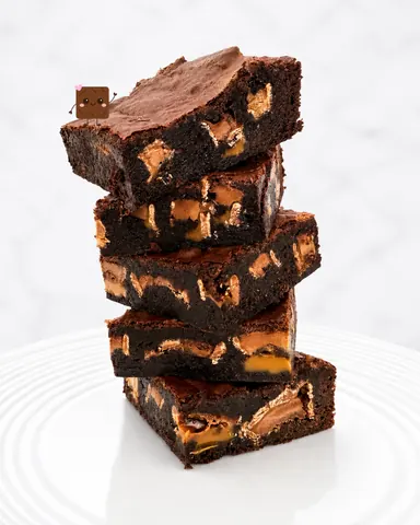 A stack of brownies with chocolate and caramel toppings.