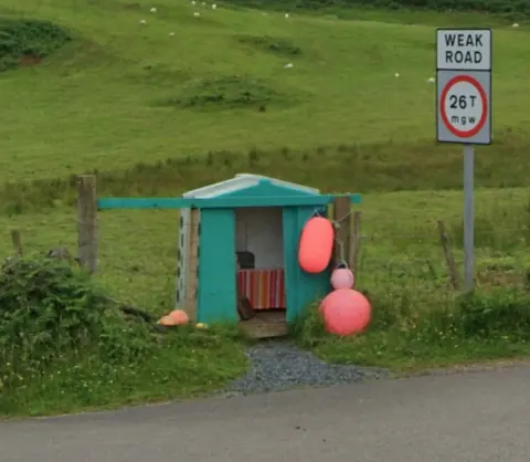 A small blue shed with a sign on it.