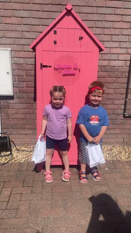 Two children standing in front of a pink door.
