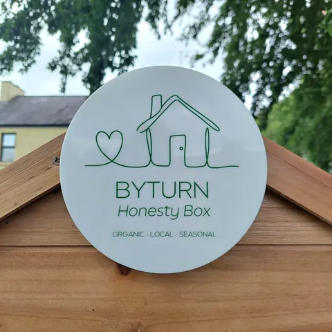A sign for a house is on a wooden post.