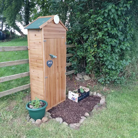 A wooden shed with a green roof and a sign on it.