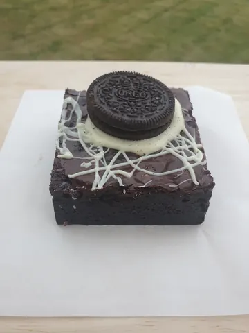 A chocolate cake with white frosting and a cookie on top.