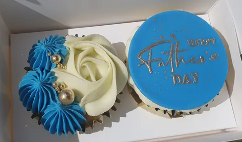 A blue cupcake with gold writing on it.