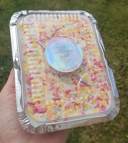 A hand holding a container of cake.
