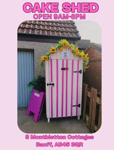 A pink and white shed with a sign on it.