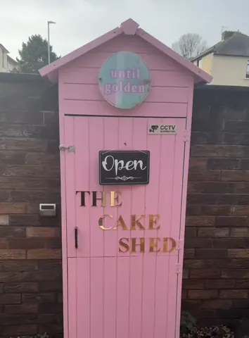 A pink door with a sign that says "The Cake Shed" on it.