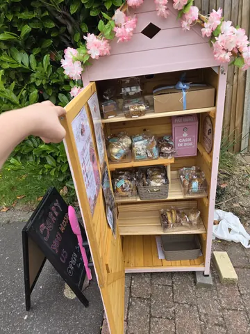 A person is holding open a pink box with a sign that says "Cake".