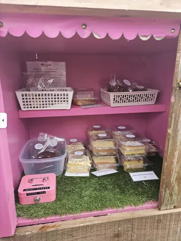 A pink and white display case with a variety of desserts.