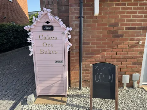 A pink shed with a sign that says open.