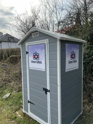 A small grey building with a sign on it.