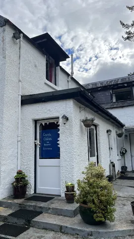 A white building with a blue sign on the door.
