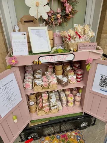 A pink cake cart with a sign that says Cherry on Top.