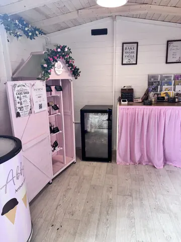A pink and white vending machine with a freezer and a refrigerator.