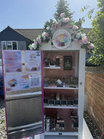 A small pink building with a white sign on it.