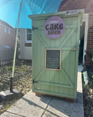 A small green building with a sign that says "Cake Shed" on it.