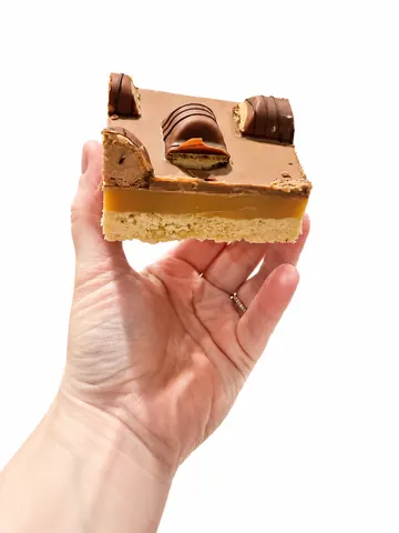 A hand holding a piece of cake.