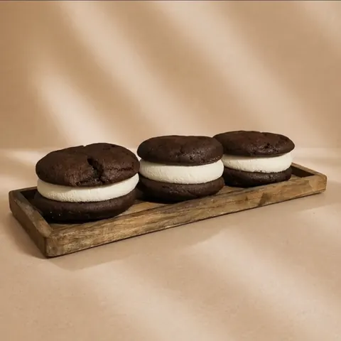 A wooden tray with three chocolate chip cookies and three white cookies.