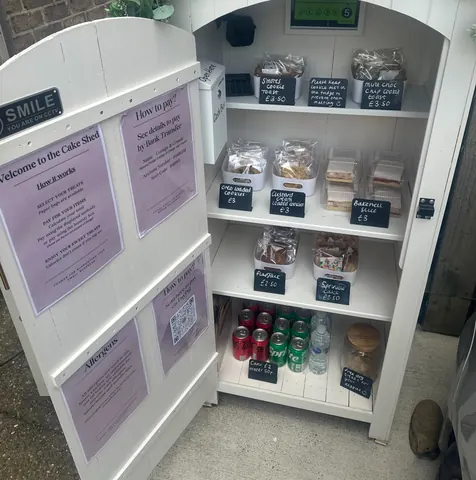 A white box with a sign that says "Smile in the Cake Shop" on it.