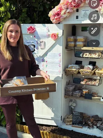 A woman is holding a box of brownies.