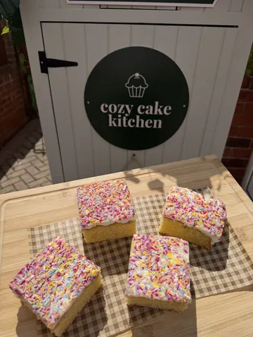 A wooden table with a sign that says Cozy Cake Kitchen.