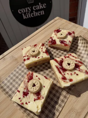 A wooden cutting board with four slices of cake on it.