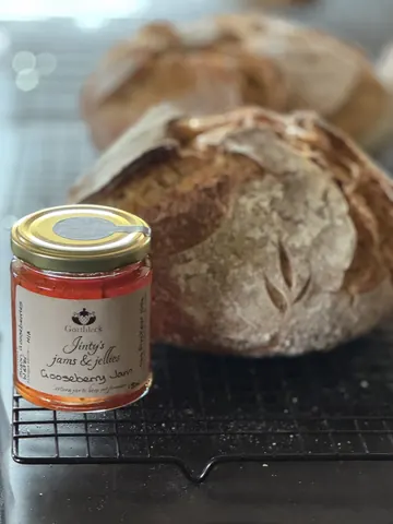 A jar of jam is sitting next to a loaf of bread.
