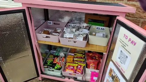 A pink display case with a variety of food items inside.