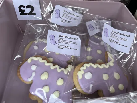 A box of cookies with purple icing and white icing.