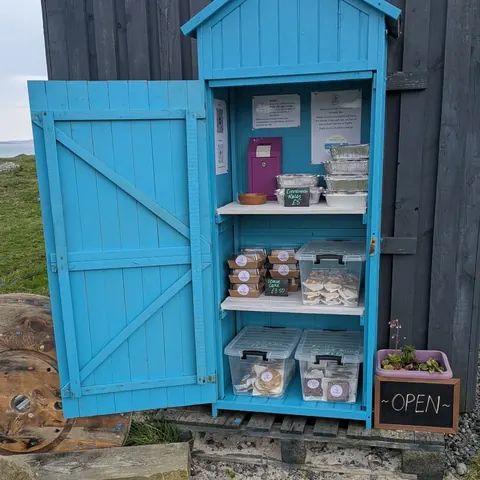 A blue shed with a sign that says open.