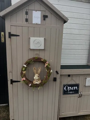 A small wooden hut with a wreath and a sign that says "open".