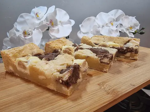 A wooden table with two square pieces of cake on it.