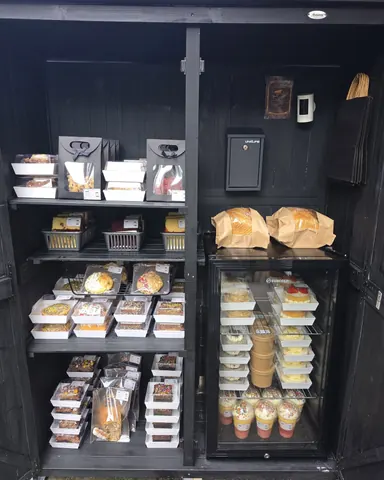 A black refrigerator with a white door and a shelf full of food.