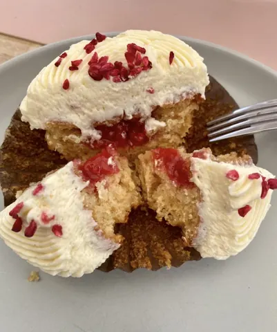 A slice of cake with white frosting and red berries.