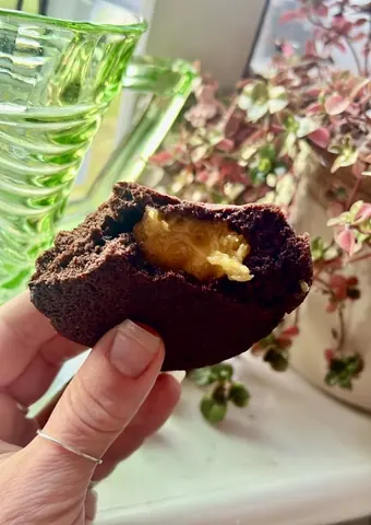 A person is holding a chocolate dessert in their hand.