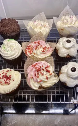 A tray of cupcakes with various frosting and decorations.