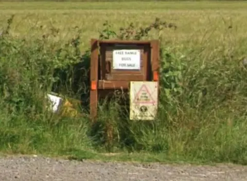A sign in the grass that says face bags for sale.