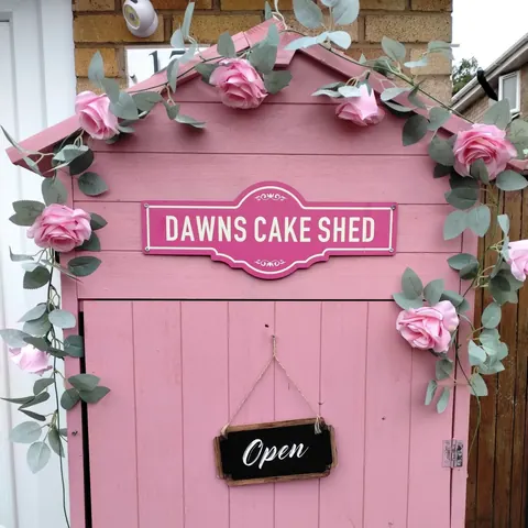 A pink building with a sign that says "Dawns Cake Shed" on it.