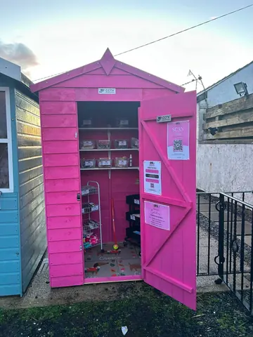 A pink shed with a sign on the door.