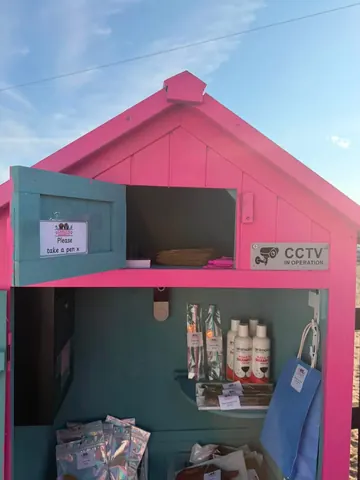 A pink and blue house with a sign that says "take a pen".