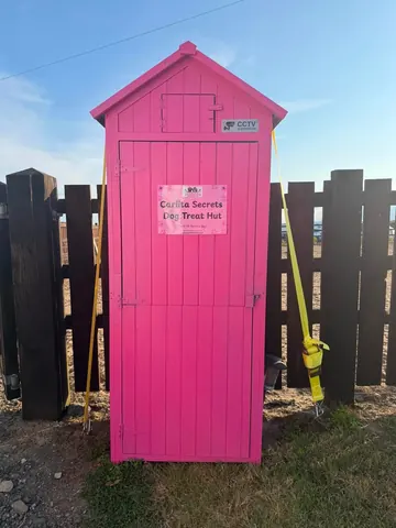 A pink shed with a yellow rope.
