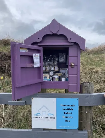 A purple shed with a sign that says "Homemade Scottish Heath Hut".