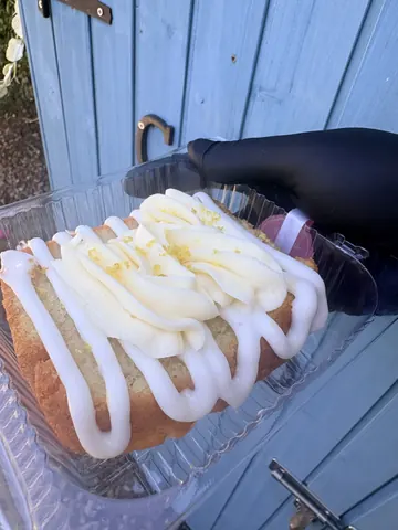 A slice of cake with white icing and lemon on top.