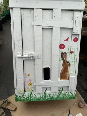 A white door with a rabbit and flowers painted on it.