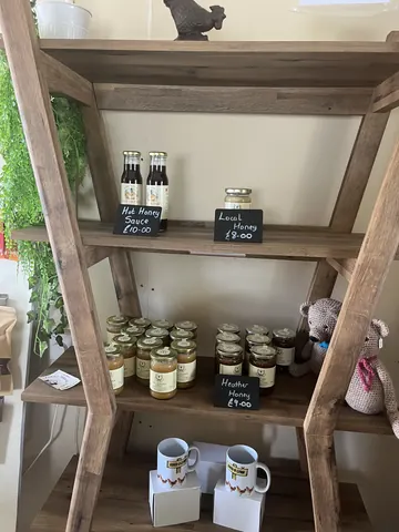 A wooden shelf with jars of jam on it.