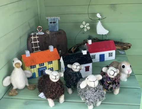 A collection of stuffed animals, including sheep, are displayed on a table.