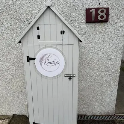 A white shed with a sign on it.
