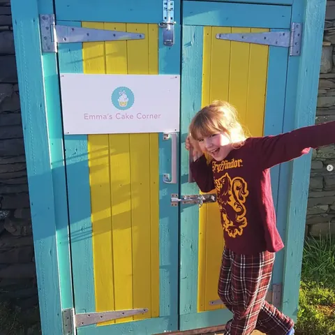 A girl is standing in front of a blue and yellow door.