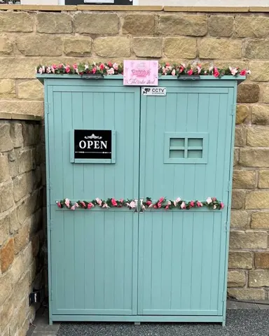A blue shed with pink flowers on it.