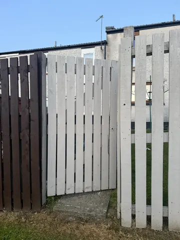 A white fence with a brown wooden slat.